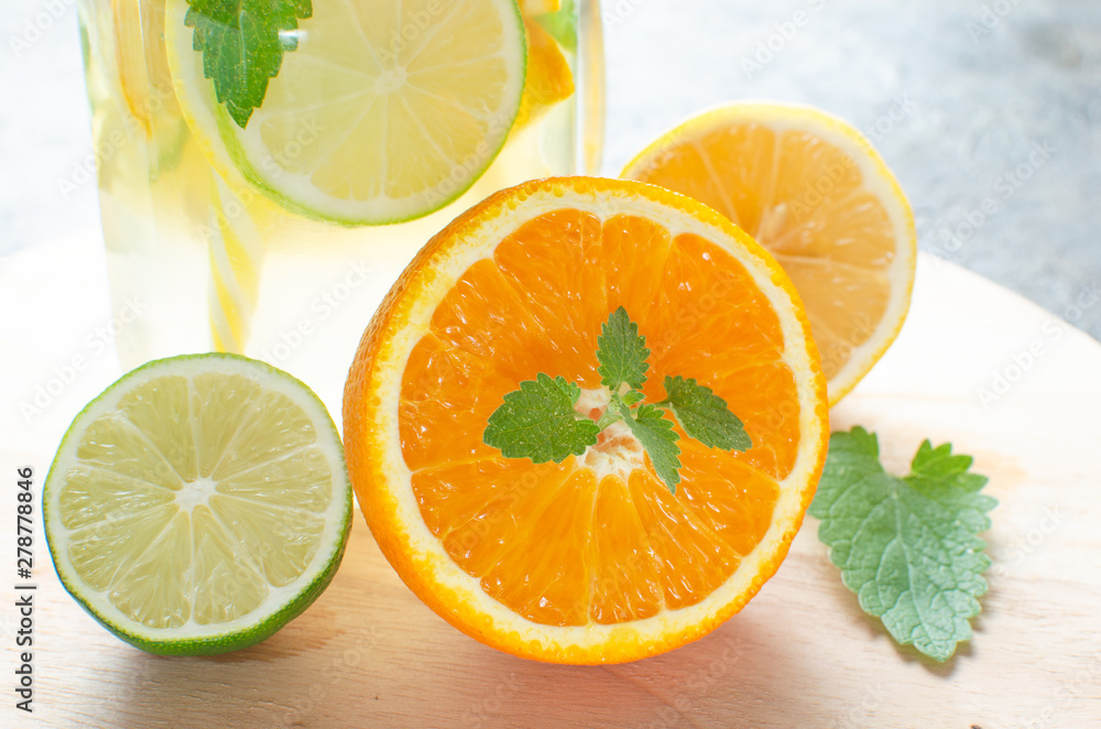 Jar of lemonade made of lemon, lime, orange and mint with a closed lid and a tube in it against background concrete floor. Jar of lemonade made of lemon, lime, orange and mint with a closed lid and a tube in it against background concrete floor.