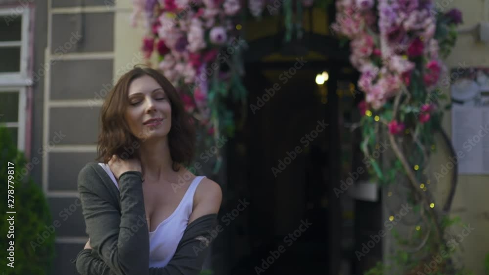 Happy woman portrait sexy moving on the flower arch background in beautiful Riga old town - Wearing white t-shirt Happy woman portrait sexy moving on the flower arch background in beautiful Riga old town - Wearing white t-shirt