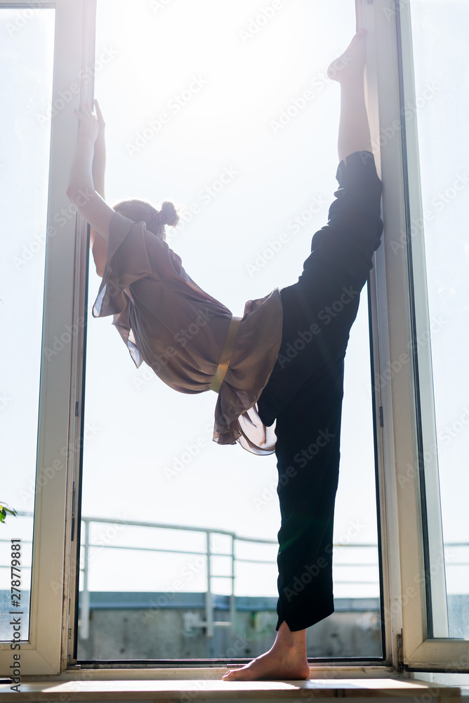 Young attractive girl doing yoga in the window opening. Physical culture, healthy life concept. Young attractive girl doing yoga in the window opening. Physical culture, healthy life concept.