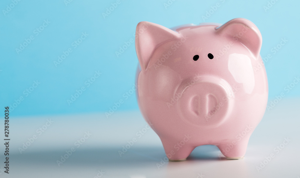 Pink piggy bank for coins savings on blue background
