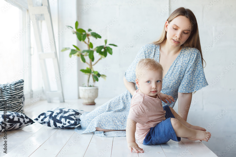 Φωτογραφία Young mom and cheerful adorable tot boy playing, having fun together at home on white wooden floor, mother playfully сalling and asking his son to take first steps