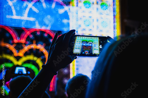 Light and music performance recorded with a smartphone held by a woman’s hand during Cuneo Illuminata (Illuminated Cuneo), traditional public fair in Cuneo (Piedmont, Italy)