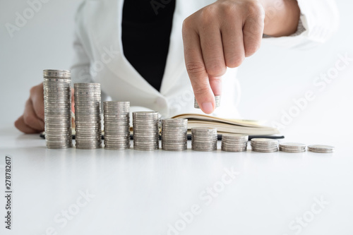 one woman putting coins on growth coins graph in white suit.