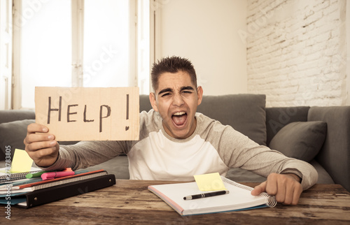 Young desperate student in stress working and studying holding a help sign. photo