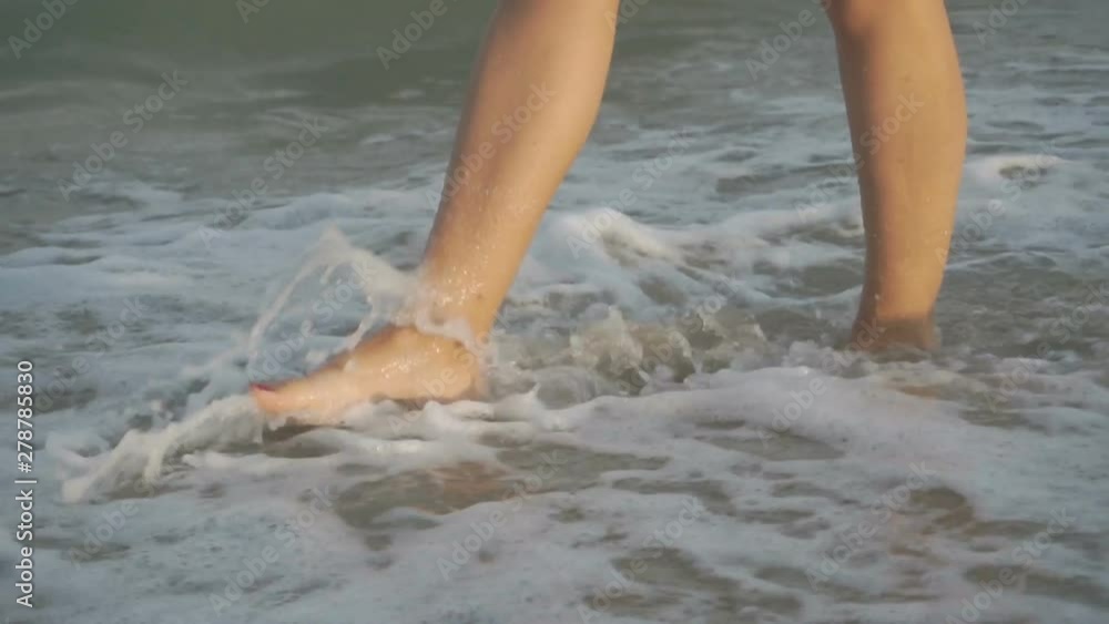 Track shot on the woman's legs while walking in the beach Track shot on the woman's legs while walking in the beach