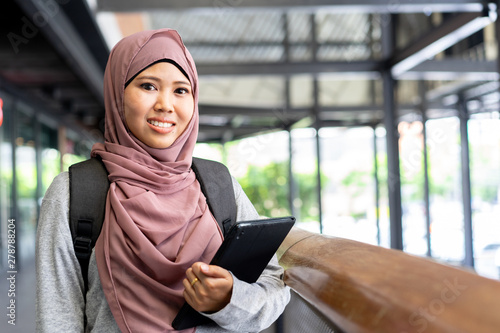 close up young beautiful malaysian student woman smiling and holding tablet at school buildings outside for study abroad concept photo