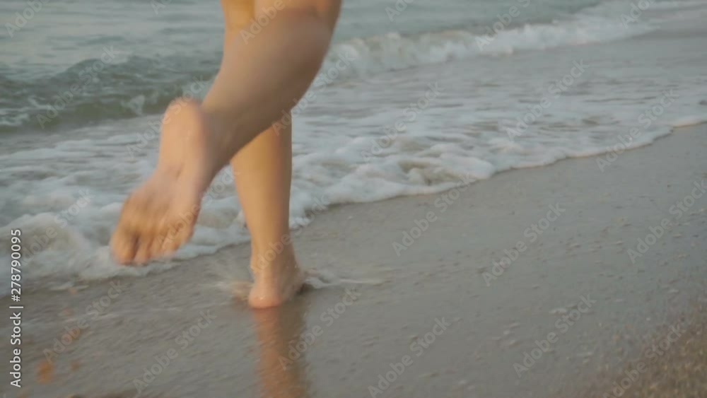 Track shot on the woman's legs while walking in the beach Track shot on the woman's legs while walking in the beach