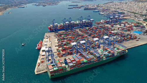 Aerial drone view of industrial cargo shipment and logistics port terminal with container trucks, ships and cranes