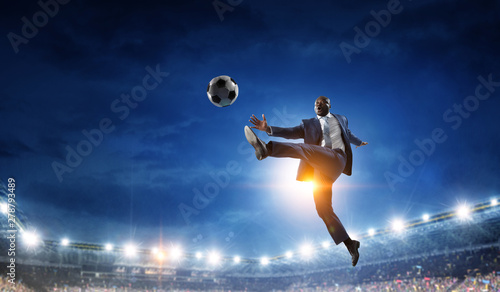 Black businessman in a suit playing footbal