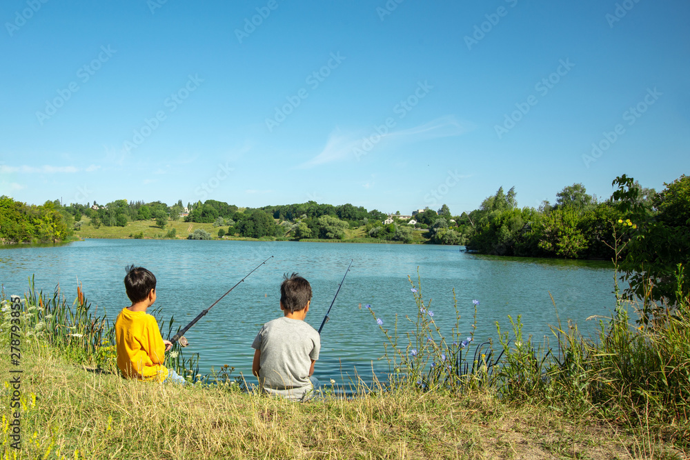 Two boys with fishing rods catch fish on the pond with a grandfather. Two boys with fishing rods catch fish on the pond with a grandfather.