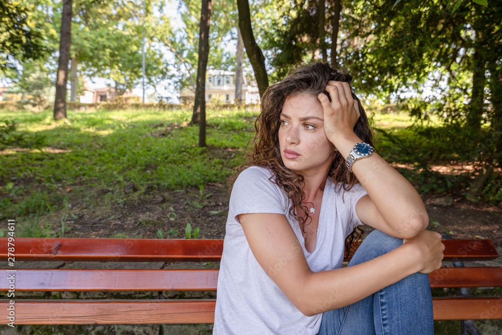 Young girl or woman sitting alone on the park bench feeling depressed and sad after she had argue and fight with her boyfriend or husband and she thinking about her life with sadness on her face Young girl or woman sitting alone on the park bench feeling depressed and sad after she had argue and fight with her boyfriend or husband and she thinking about her life with sadness on her face