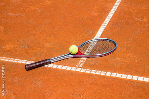 Tennis ball and racket on a clay court close-up