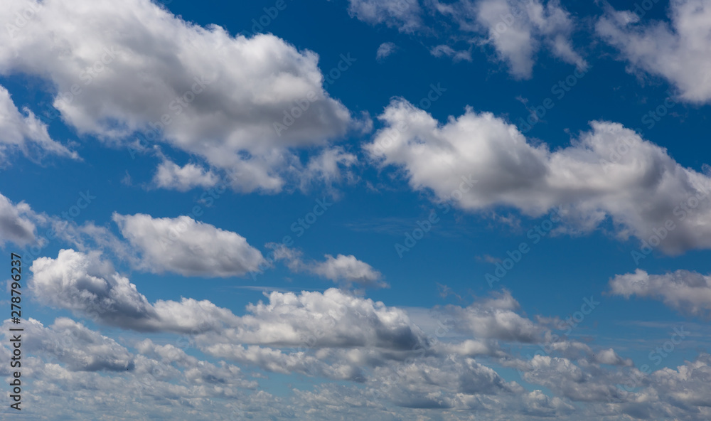 Cumulus fluffy clouds in the blue sky. Harbingers of rain. Sky pattern.