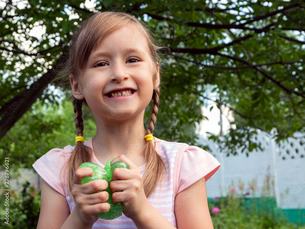 Little cute girl plays in the popular toy anti-stress for hands, chewing gum for hands, slime. Metalic color. Games for children and adults. Free space for text.