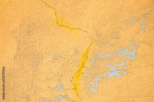 Yellow bright wall texture background with a crack