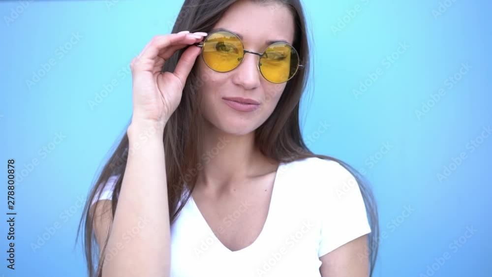 Portrait of beauty fashion smiling hipster girl in sunglasses on blue background. Outdoor Portrait of beauty fashion smiling hipster girl in sunglasses on blue background. Outdoor