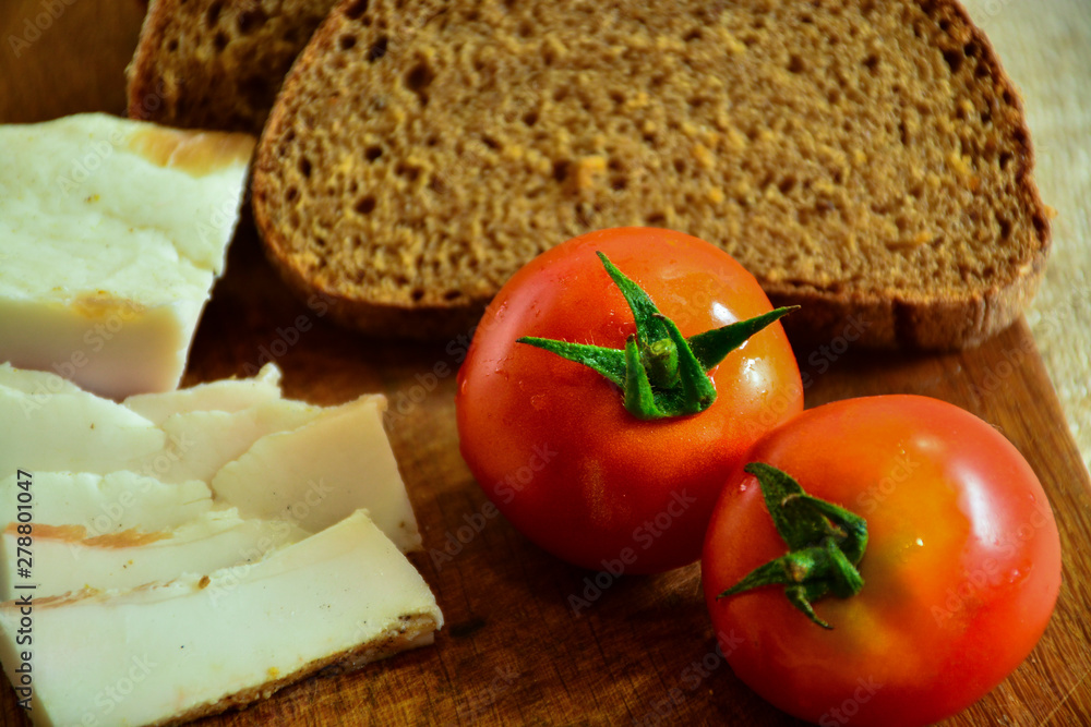  Freshly baked bread on a wooden cutting board with bacon and tomatoes