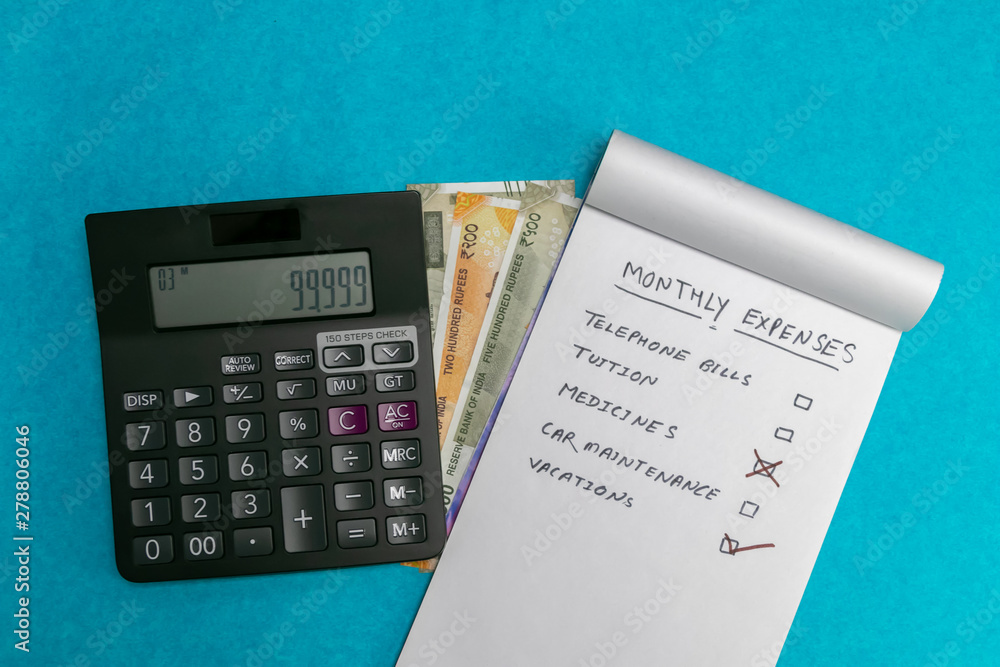 Written notepad and calculator on Indian currency and blue background. Medicine and Expense concept Written notepad and calculator on Indian currency and blue background. Medicine and Expense concept