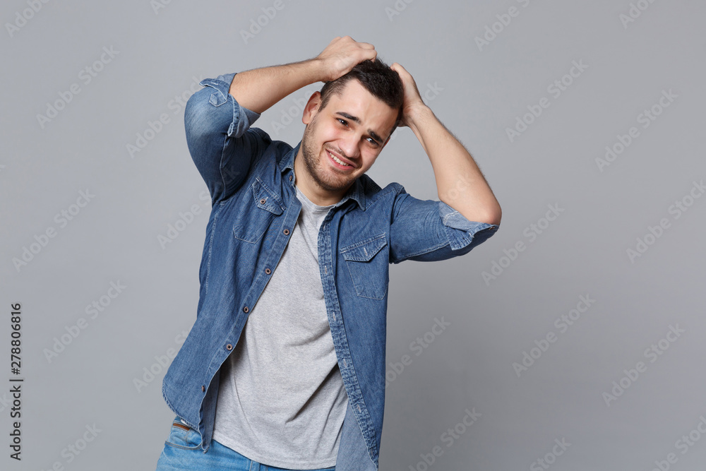 Angry mad sad upset unshaven young man in denim jeans shirt posing isolated on grey wall background studio portrait. People sincere emotions lifestyle concept. Mock up copy space. Screaming gesturing. Angry mad sad upset unshaven young man in denim jeans shirt posing isolated on grey wall background studio portrait. People sincere emotions lifestyle concept. Mock up copy space. Screaming gesturing.