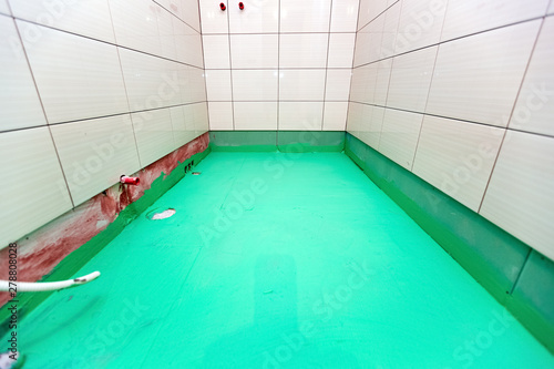 Bathroom with tiled walls and floor painted by green colored waterproof finish material in apartment is inder construction, remodeling, renovation, overhaul, extension, restoration and reconstruction photo