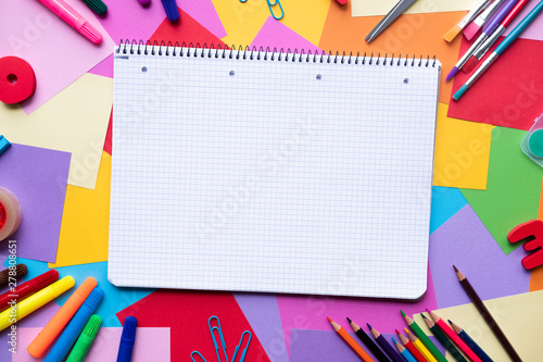 Notebook with school supplies on colorful background with copy space