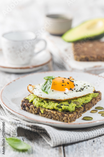 Sandwich with avocado, egg and spinach on white wooden background. Healthy diet breakfast