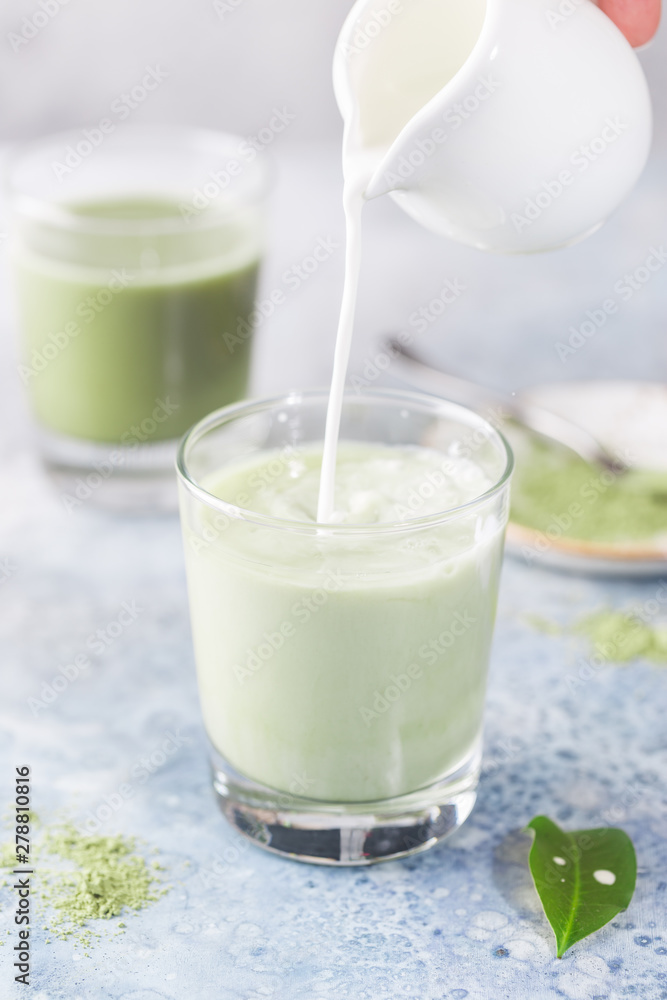 Iced Matcha green latte in glasses with matcha powder on light background. Iced Matcha green latte in glasses with matcha powder on light background.