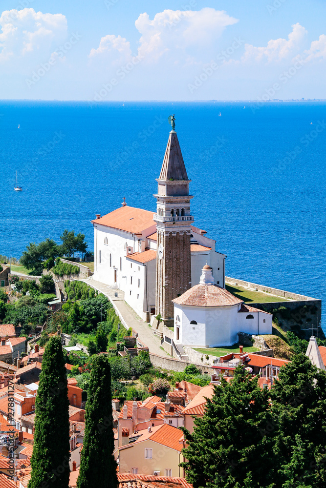 View of St George's Church and the red tiled rooftops of the old town of Piran in Slovenia, with the Adriatic Sea in the background