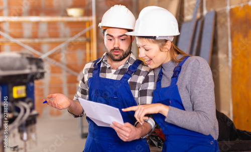 Workers man and woman discuss construction plan