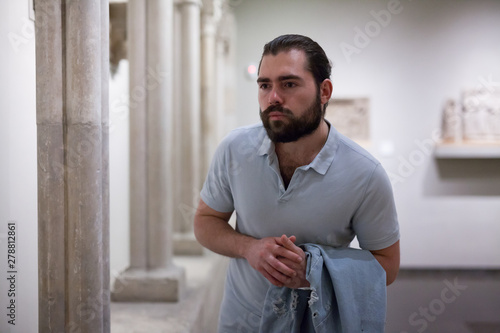 Man visiting sculpture hall in historical museum and looking at exhibits