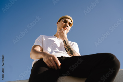 Low angle view of man sitting on wall against sky