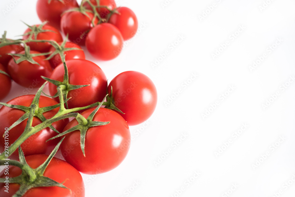Branch of a fresh red tomato cherry, isolated on a white background corner composition Branch of a fresh red tomato cherry, isolated on a white background corner composition