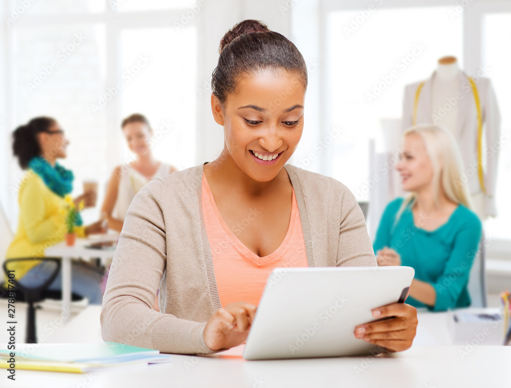 technology, clothing and tailoring concept - smiling african american female fashion designer with tablet computer over studio and colleagues on background technology, clothing and tailoring concept - smiling african american female fashion designer with tablet computer over studio and colleagues on background