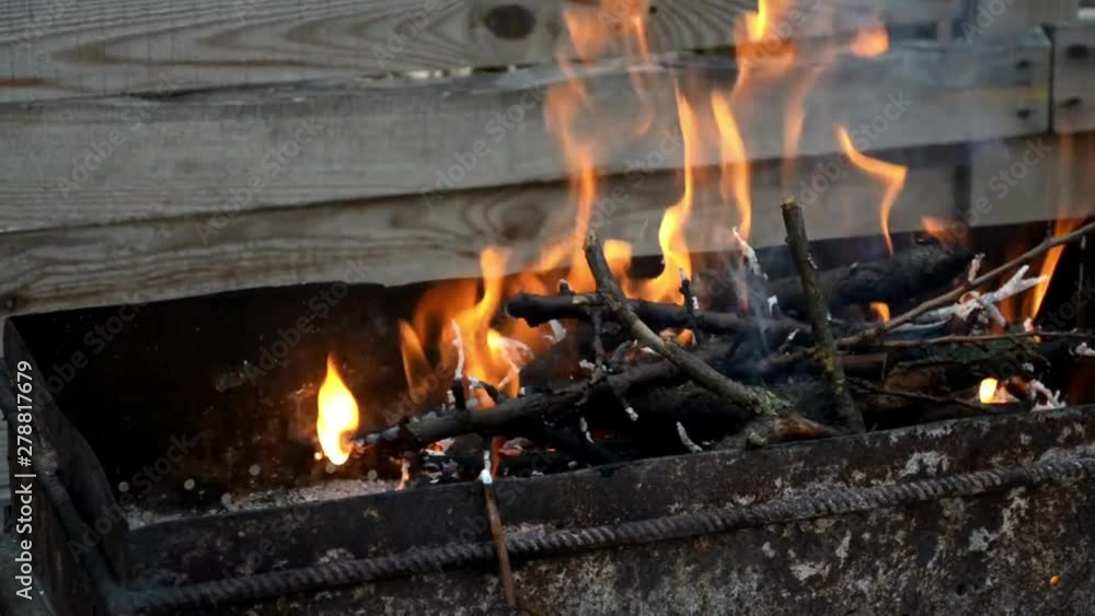Bright orange fire burns in a black metal grill with brunches Bright orange fire burns in a black metal grill with brunches