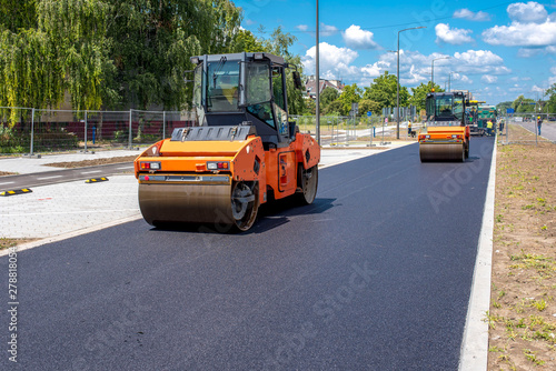 Vibratory asphalt roller compactor on site, compacting new asphalt pavement in urban modern city