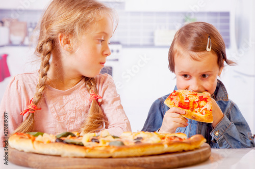 We love pizza  Cute little child girls eating pizza.