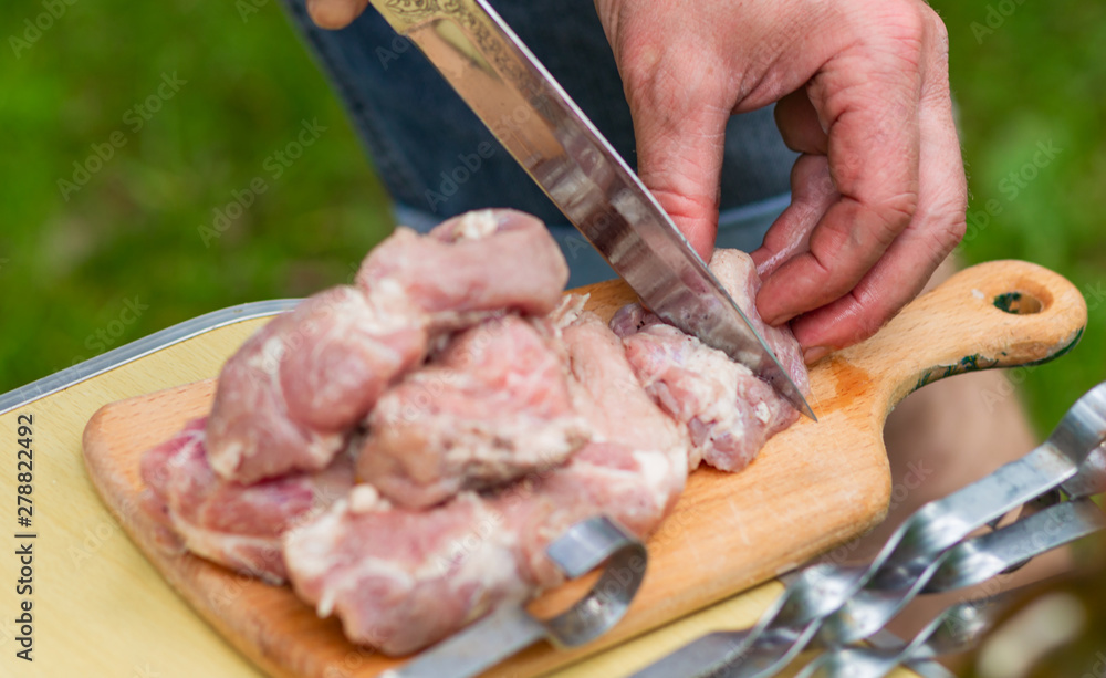  men's hands sliced marinated raw meat into pieces with a sharp metal knife