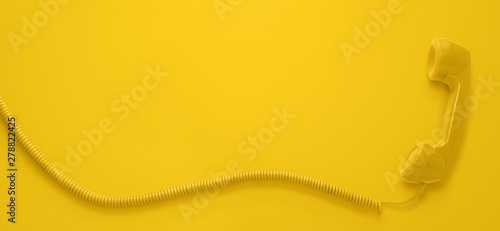 Vintage telephone handset isolated on yellow background with copy space