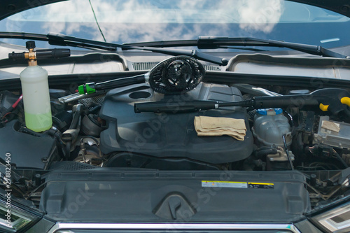 The open engine compartment of the car with accessories for washing. Close-up view