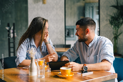 young couple using their tablet during a coffee date