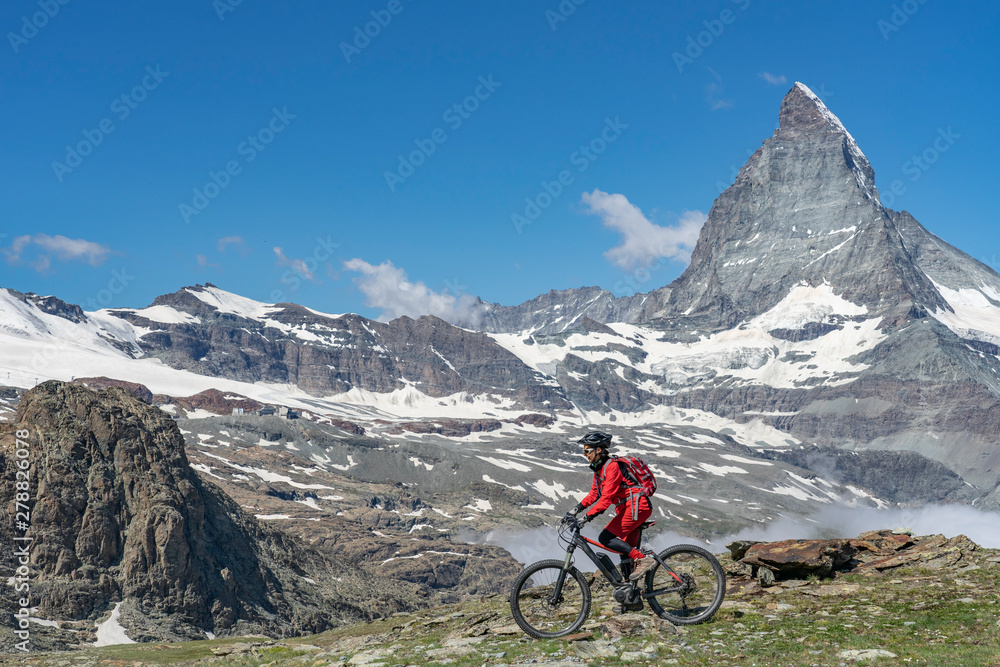 Fototapeta premium aktywna starsza kobieta na swoim elektrycznym rowerze górskim pod słynnym Matterhorn w Zermatt, Wallis, Szwajcaria