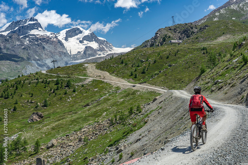 active senior woman, riding her electric mountainbike below the famous Gornergrat in Zermatt, in the background Rimpfischhorn and Strahlhorn,Wallis,Switzerland
