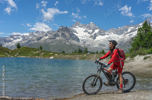 nice senior Woman riding her electric mountain bike at the Stelli Lake below Blauherd and Sunnegga, Zermatt, Valais,Wallis,Switzerland, in the background Strahlhorn and Cima de Jazzi