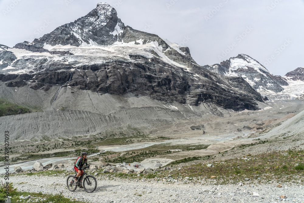 Fototapeta premium active senior woman, riding her electric mountainbike below the famous Matterhorn in Zermatt, Wallis,Switzerland