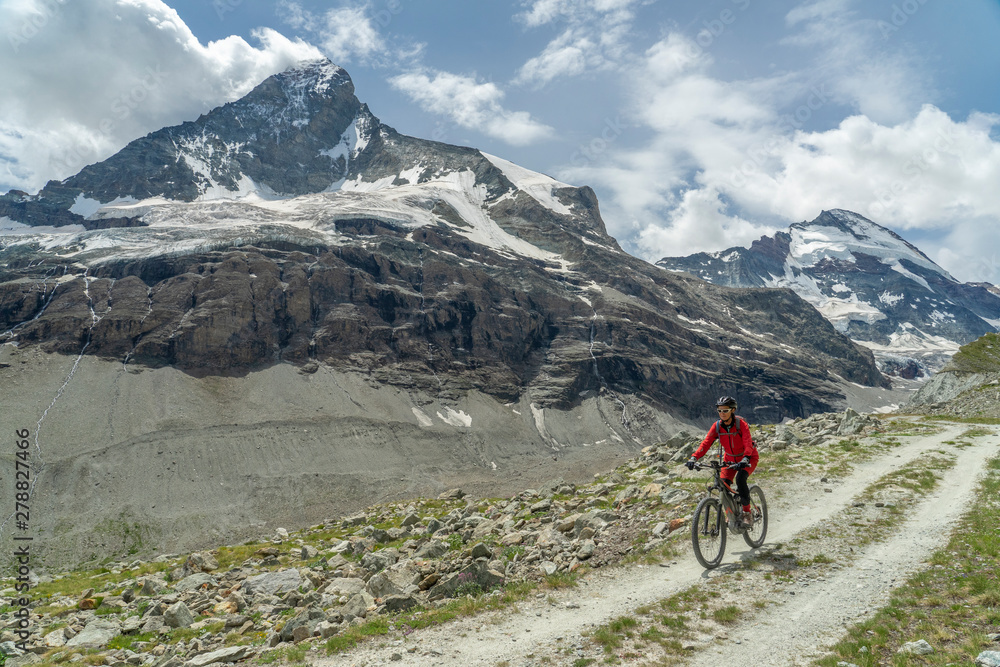 active senior woman, riding her electric mountainbike below the famous Matterhorn in Zermatt, Wallis,Switzerland