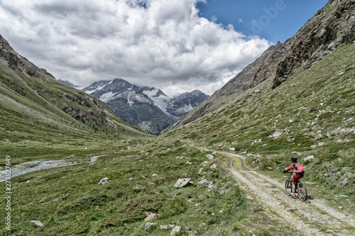 nice and ever young senior woman riding her electric mountainbike up to the Taeschalp, near Zermatt, Cantone Valais, Wallis, Switzerland photo