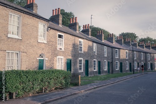 Row of restored Victorian brick houses with green colored doors and white windows. © drimafilm