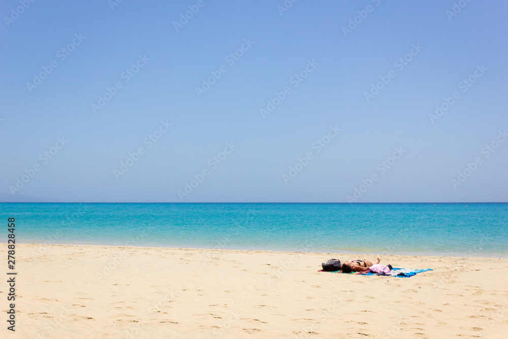 Lonely woman sunbathing on empty beach. Female tourist enjoying summer holidays on paradise island with turquoise water sea. Travel vacation, unique destination concepts