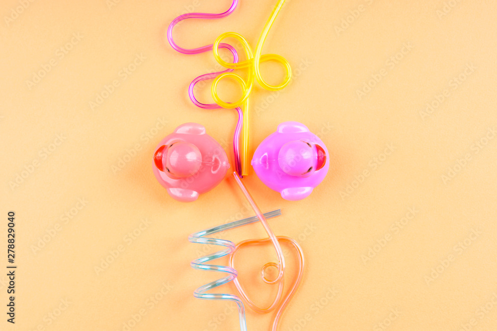 Party cocktail straws and rubber ducks on orange. Flat lay on orange pink background. Copy space