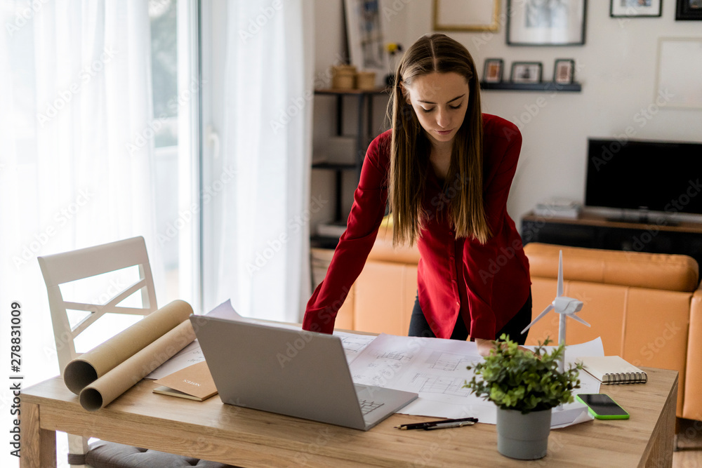 Woman in office working on plan with wind turbine model on table Woman in office working on plan with wind turbine model on table